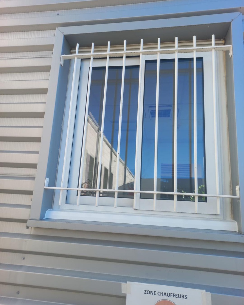 Grille de défense en acier thermolaqué blanc sur fenêtre coulissante aluminium